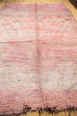 Plush Moroccan carpet, showing overdyed cranberry and violet coloration and tattered ends.