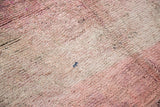 Textured wool pile of vintage Moroccan rug with overdyed soft cranberry and beige tones.
