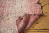 Plush wool pile of vintage Moroccan carpet showing striped hand-knotted foundation and tattered edge.