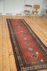 Distressed Malayer runner with red paisley field, diamond medallions, geometric borders.