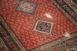 Distressed Malayer runner, cherry red field with boteh, navy medallion, and visible foundation.