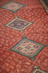 Distressed Malayer rug shows worn cherry red field, allover paisley, and geometric teal medallion.