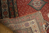 Distressed Malayer runner showing worn cherry red field and geometric patterned foundation.