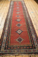 Tattered fringe and worn geometric border on a distressed cherry red Malayer runner.