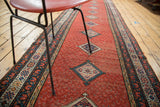 Distressed Malayer runner showing cherry red field, diamond medallions, and geometric border.