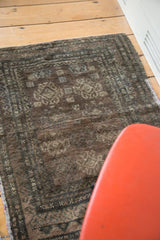 Distressed texture of a geometric Oushak rug with faded medallions and dark tones.