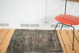 Distressed Oushak rug corner with geometric border and dark medallion patterns.