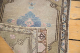 Folded corner of vintage Oushak rug, showing hand-knotted foundation and floral pattern.