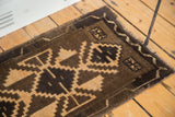 Geometric pattern of an Oushak rug with dark brown outlines and beige fill, showing wear.