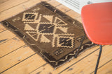 Densely woven Oushak rug mat corner with brown geometric patterns and fringe.