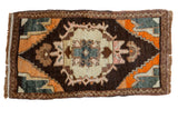Vintage Oushak rug with a bursting medallion on a charcoal brown field, colorful floral spandrels.