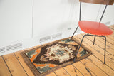 Corner view of the vintage Oushak rug with tangerine and teal spandrel on charcoal field.