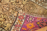 Vintage Oushak rug secured end with fringe, showing magenta and earth-toned geometric patterns.
