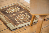 Corner of vintage Oushak rug with brown field, geometric pinwheel motifs, and light border.