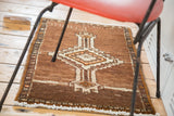 Vintage Oushak mat displaying tribal diamond medallion on coffee brown field with geometric border.