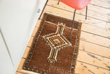 Vintage Oushak rug mat showing lower right corner with ISHMAEL weaver name on coffee brown field.