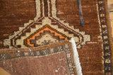 Vintage Oushak rug's folded corner reveals hand-knotted geometric pattern and fringe.
