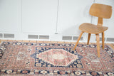 Distressed Oushak rug featuring a bold navy medallion against soft blush and sand tones.