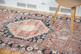 Distressed Oushak rug with blush rose, navy, and sand geometric floral patterns.