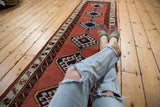 Faded brick red Sarab runner with navy hexagonal medallions and reciprocating water motif border.