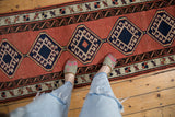 Vintage Sarab runner close-up: navy diamond medallions, faded brick red field, dark water motif.