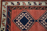 Vintage Sarab rug detail showcasing navy geometric medallion, water motif border, and brick red field.