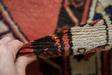 Thick full pile and secured side selvage of a vintage Sarab rug in brick red and charcoal.