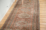 Distressed brick red Karaja runner with hooked geometric medallions and blue-green accents.