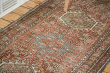 Vintage Karaja runner with distressed brick red field, geometric medallions, and detailed border.