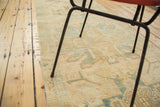 Secured edge of vintage Oushak runner, with gold and faded teal rectilinear patterns.