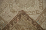 Textured close-up of distressed vintage Oushak rug's low pile with subtle silver-bronze tones and folded edge.