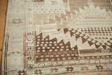 Corner of a vintage Oushak rug, showing serrated geometric designs in brown and ivory tones.