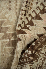 Textured fold of a vintage Oushak runner, displaying bold serrated brown rectilinear patterns.