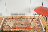 Vintage Oushak rug mat displaying diminutive rams horn medallion, blush, and orange geometric patterns.