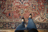 Vintage Heriz carpet with vibrant geometric patterns in madder red, navy blue, and ivory.