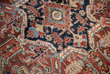Ornate geometric details of a vintage Heriz rug in madder red, navy, and ivory.