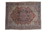 Vintage Heriz carpet with sprawling geometric medallion, serrated spandrels, brick red, navy, and ivory tones.