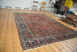 Vintage Heriz carpet displaying geometric floral motifs in navy blue and rich wine red.