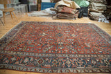 Vintage Heriz rug corner with geometric navy border, red field of serrated leaves.