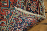 Vintage Heriz carpet corner showing bold red-navy pattern, secure fringe, and hand-knotted back.