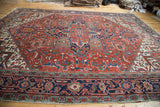 Vintage Heriz rug with detailed navy geometric border and red field palmettes.