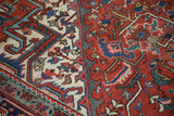 Traditional Heriz carpet with geometric pattern in brick red, ivory, and blue.