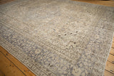 Distressed Oushak carpet corner, with faded ivory patterns and a prominent silver-grey border.