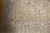 Distressed vintage Oushak carpet corner, showing muted antique ivory field and silver-grey border.