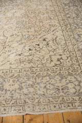 Faded ivory and silver-grey patterns on a distressed Oushak rug border.
