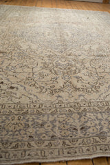 Angled detail of distressed Oushak rug, showing faded ivory, beige, and silver-grey motifs.