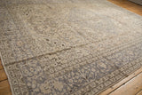 Distressed Oushak rug corner with patterned silver-grey border and antique ivory field.