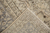 Distressed Oushak rug corner showing muted neutral pile texture and hand-knotted foundation.