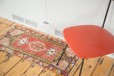 Segment of vintage Oushak rug showing faded cherry red field with geometric pinwheel and hook motifs.