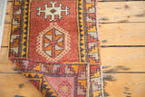 Curled corner showing reciprocating stepped geometric border on a vintage Oushak rug.